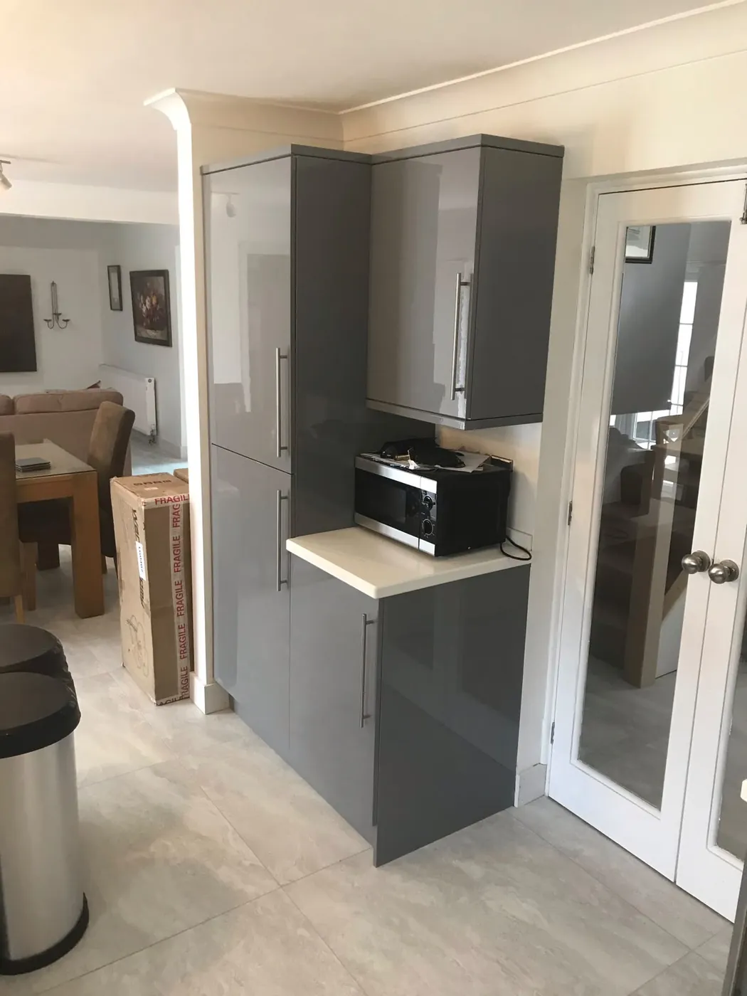 Grey gloss tall larder and wall units fitted around a doorway