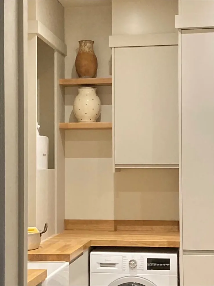Utility room with stacked laundry space, open shelves and an oak worktop